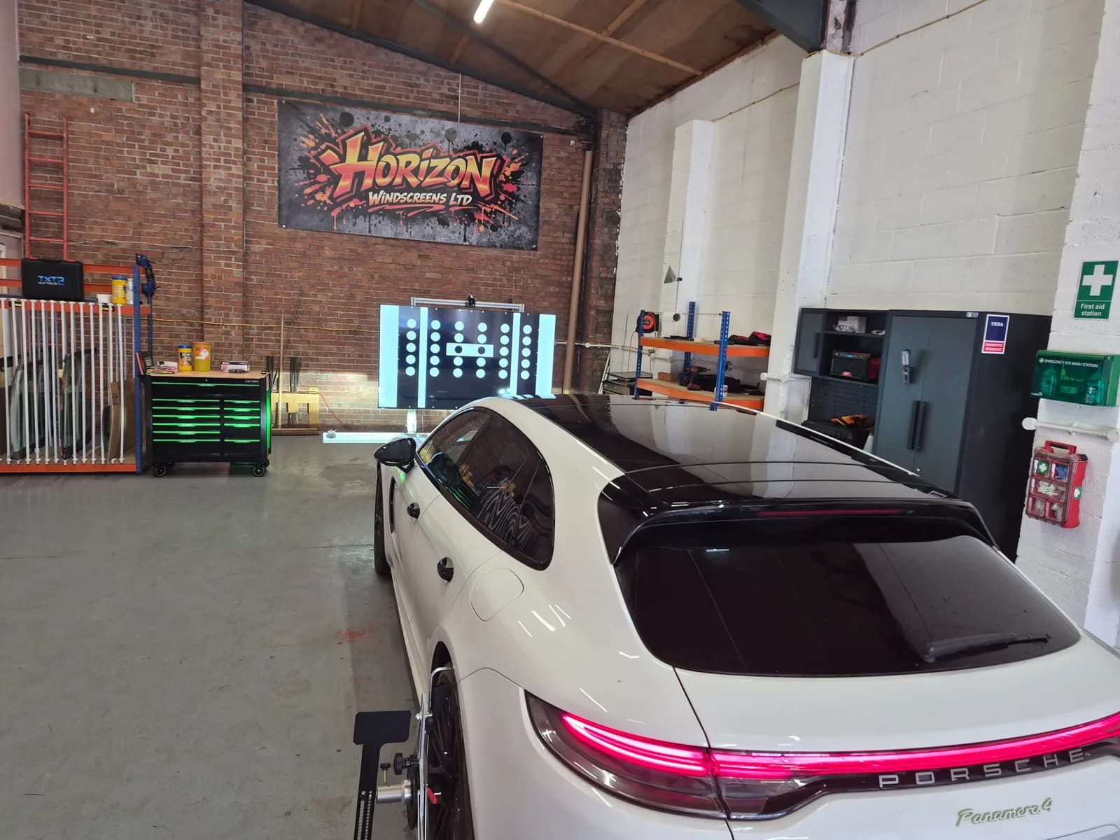 Vehicle positioned in front of an illuminated ADAS calibration target inside Horizon Windscreens' workshop.