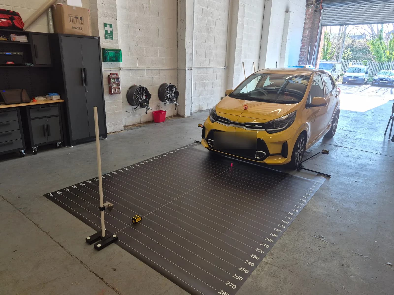 Vehicle positioned on an ADAS calibration measurement setup in the Horizon workshop.