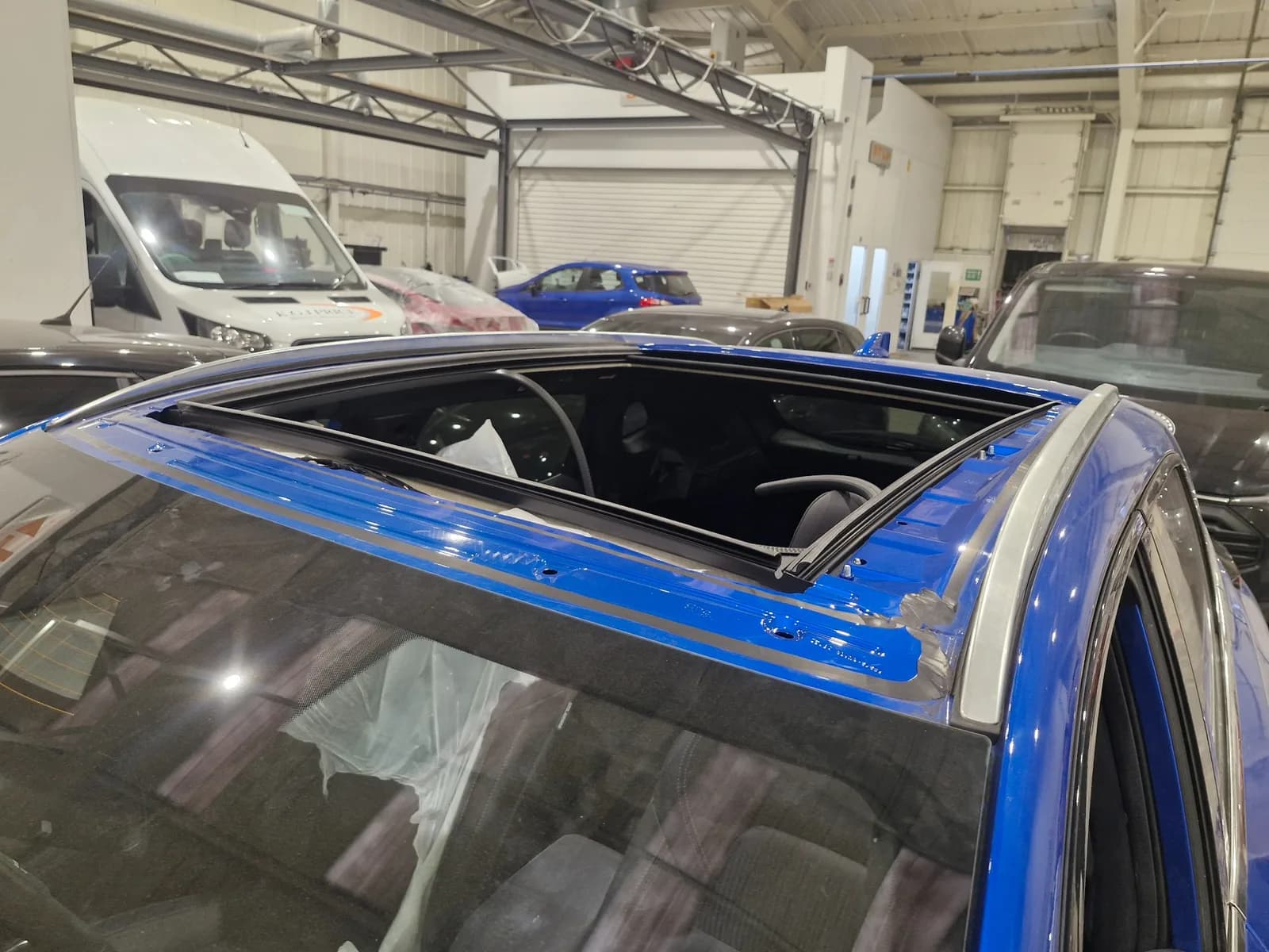 Panoramic roof glass removed from a vehicle during specialist repair work in a workshop.